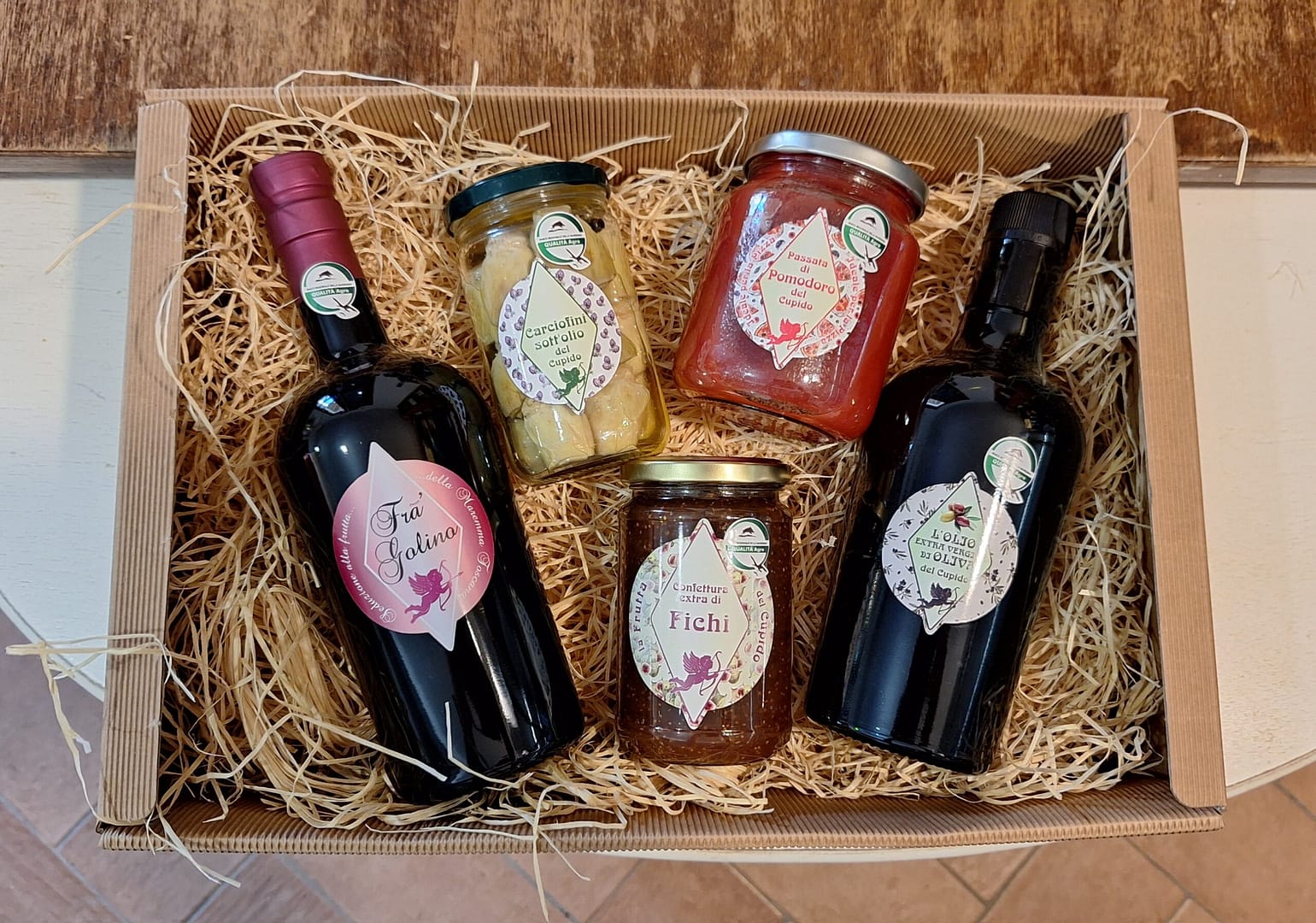 Cesto natalizio artigianale con vino, olio, passata di pomodoro, carciofini sott'olio e confettura di fichi. Prodotti tipici italiani.