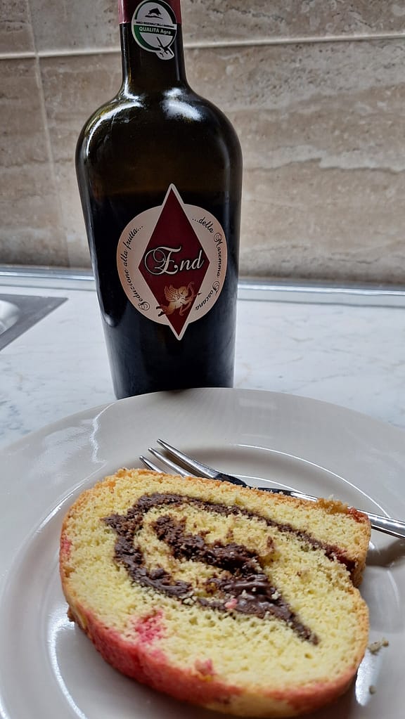 Rotolo dolce farcito al cioccolato con bottiglia di vino toscano "End". Dessert e vino italiano, delizia per il palato.